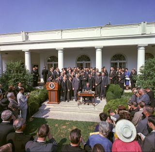Wikipedia/Cecil W. Stoughton - LBJ Library. Open Access President Johnson signing the Economic Opportunity Act, 1964