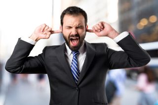 Business person covering ears over loud noise.
