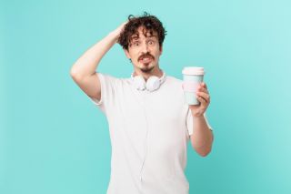 Young man feeling anxious, drinking coffee.