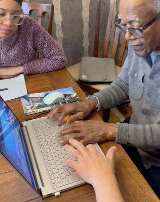 Mr. Johnson trying out the games program while his assistant, Elise Fluellen, looks on.