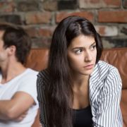 Upset couple after fight, sitting on couch looking away from each other