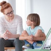 School psychologist talking to child sitting on chair