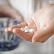 Person with a handful of pills. fizkes/Shutterstock
