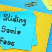 Post-its that say "Sliding Scale Fees" on yellow and blue background