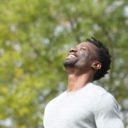 Man standing outdoors, smiling up toward the sky because he beat brain fog