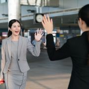 Two businesswomen waving at each other