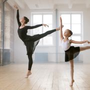Woman and young girl dancing ballet, both balancing on one toe with arm raised