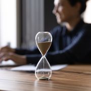 Woman working on computer next to hourglass to overcome time blindness