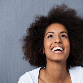 Smiling African-American woman gazes upwards with positivity