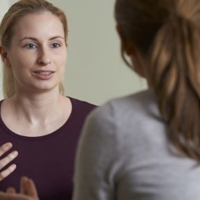 Young woman speaks with a therapist.
