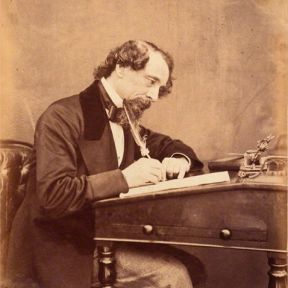 A photograph of Charles Dickens at his desk