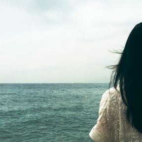Woman grieving after miscarriage looking at the sea