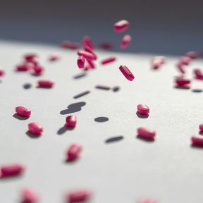 A bunch of pills hitting a white table. 