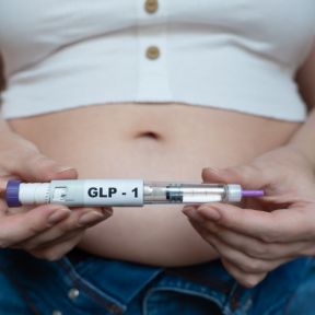Woman holding a GLP-1 injection pen. 