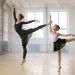 Woman and young girl dancing ballet, both balancing on one toe with arm raised