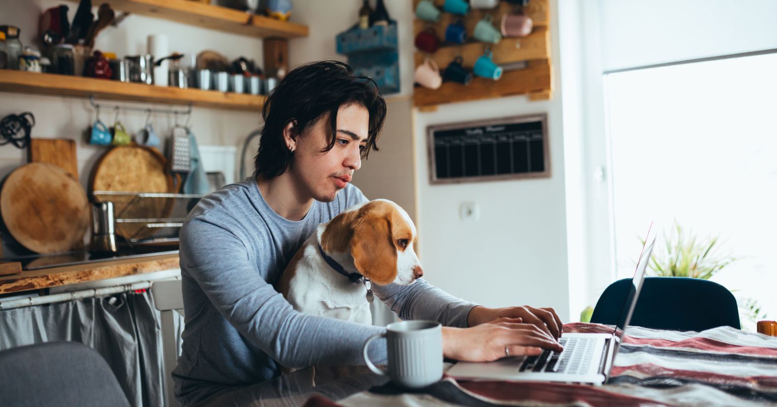 'a man sitting at a table with a dog on his lap'